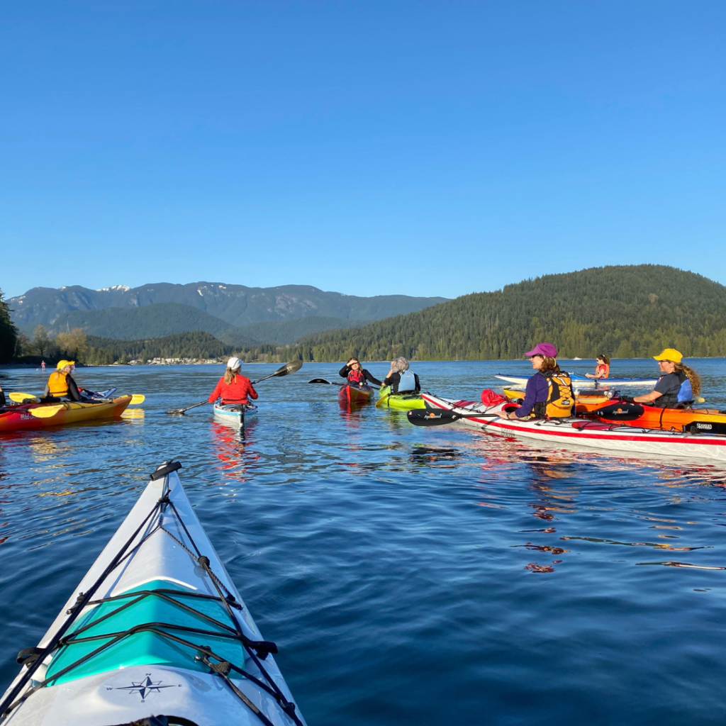 Multiple female kayakers floating on the ocean on a clear sky day