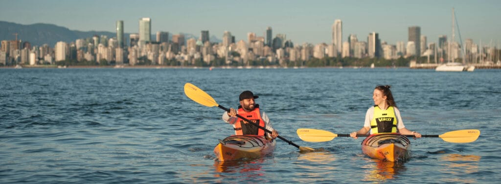 2 people kayaking with Vancouver city in the background